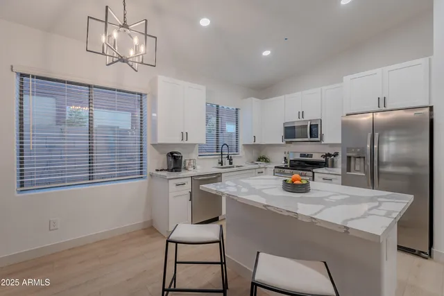 a kitchen with a refrigerator a stove a sink dishwasher a dining table and chairs with wooden floor