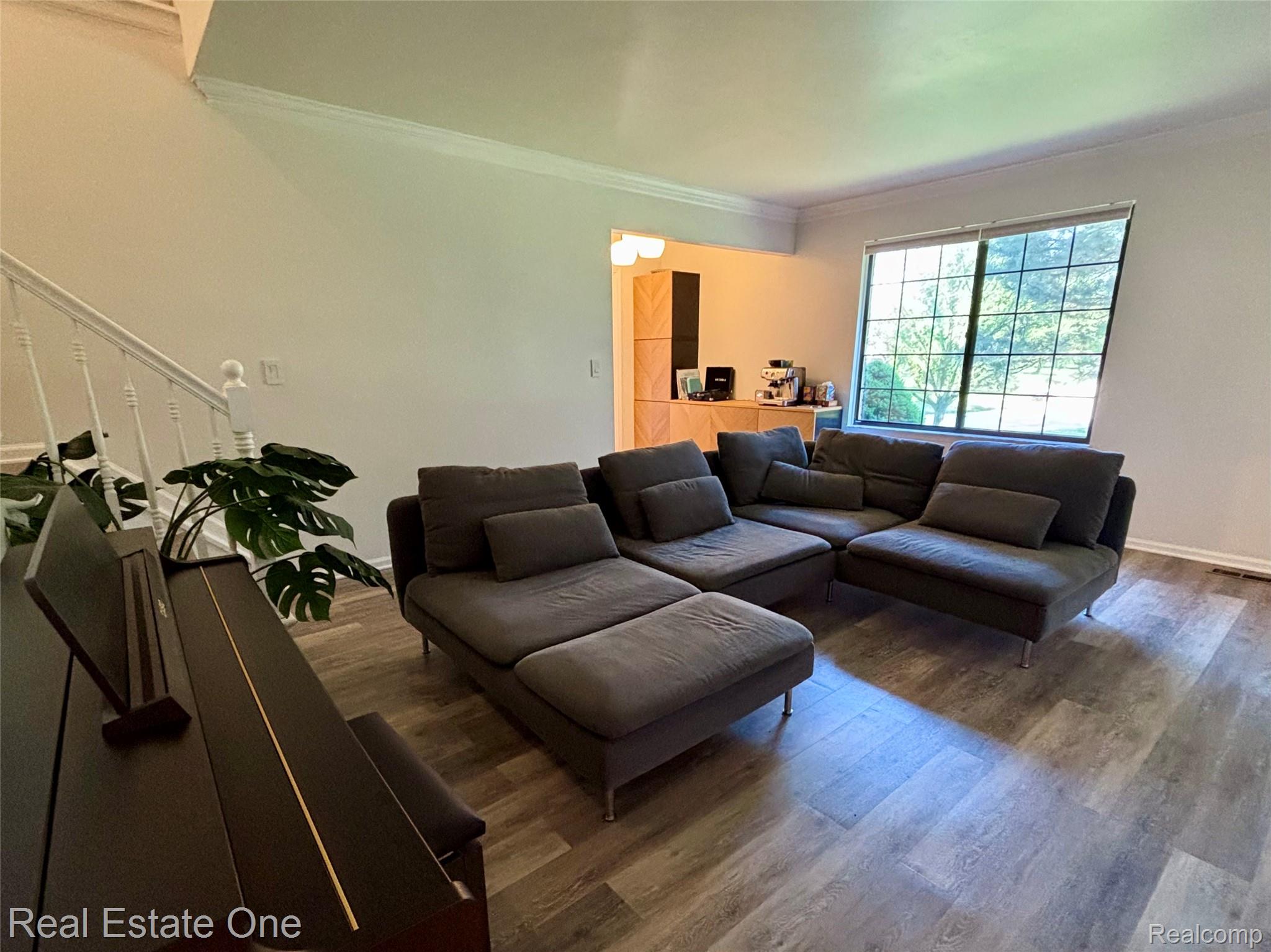 66 Meadow Wood Drive Rochester, MI 48307 - Photo 4 of 20 Spacious living area featuring wood-finish flooring, crown molding, and a large window overlooking exterior greenery