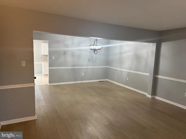 an empty room with wooden floor and mirror