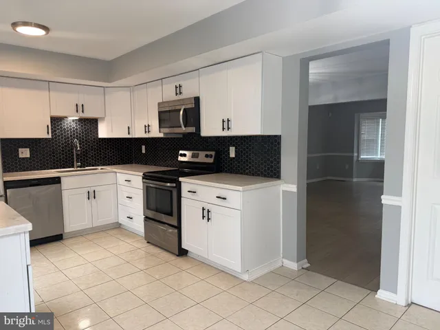 a kitchen with stainless steel appliances granite countertop a sink and white cabinets