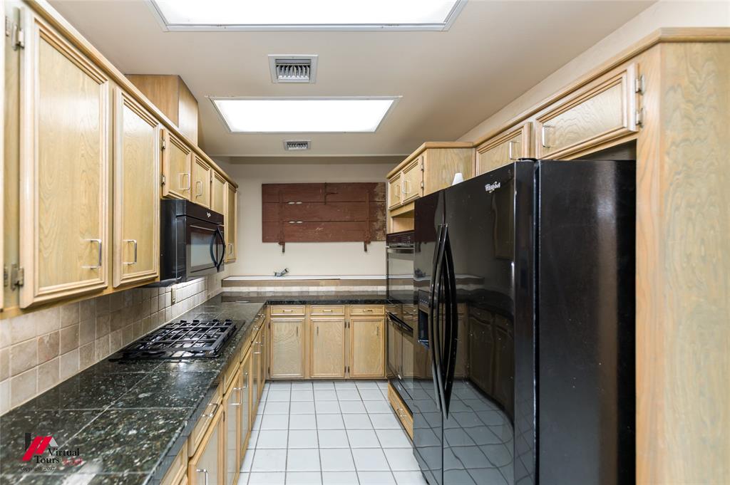 300 Pierremont Road, Unit 40 Shreveport, LA 71106 - Photo 17 of 34 U-shaped kitchen featuring wood cabinetry, black appliances, a gas range, tile countertops, and tile flooring