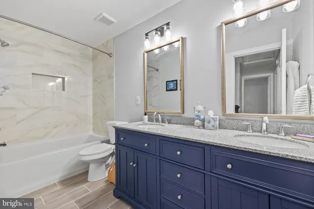 a bathroom with a granite countertop sink toilet mirror and bathtub