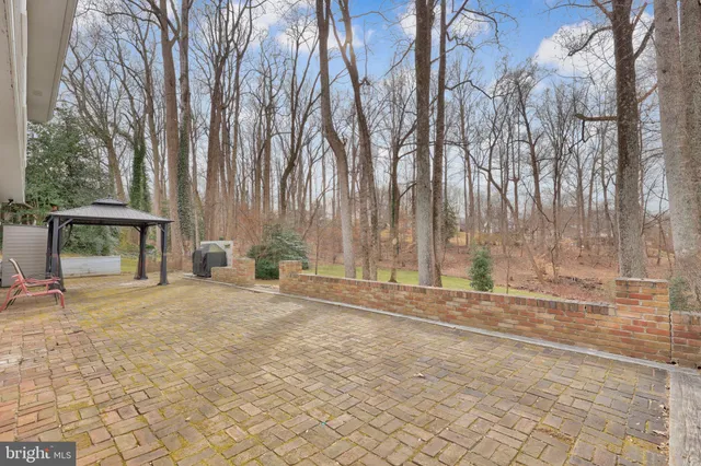 a view of backyard with white fence and large trees