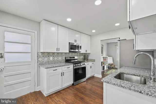 a kitchen with granite countertop a sink stainless steel appliances and cabinets