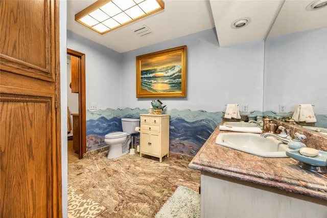 a bathroom with a granite countertop sink mirror and toilet