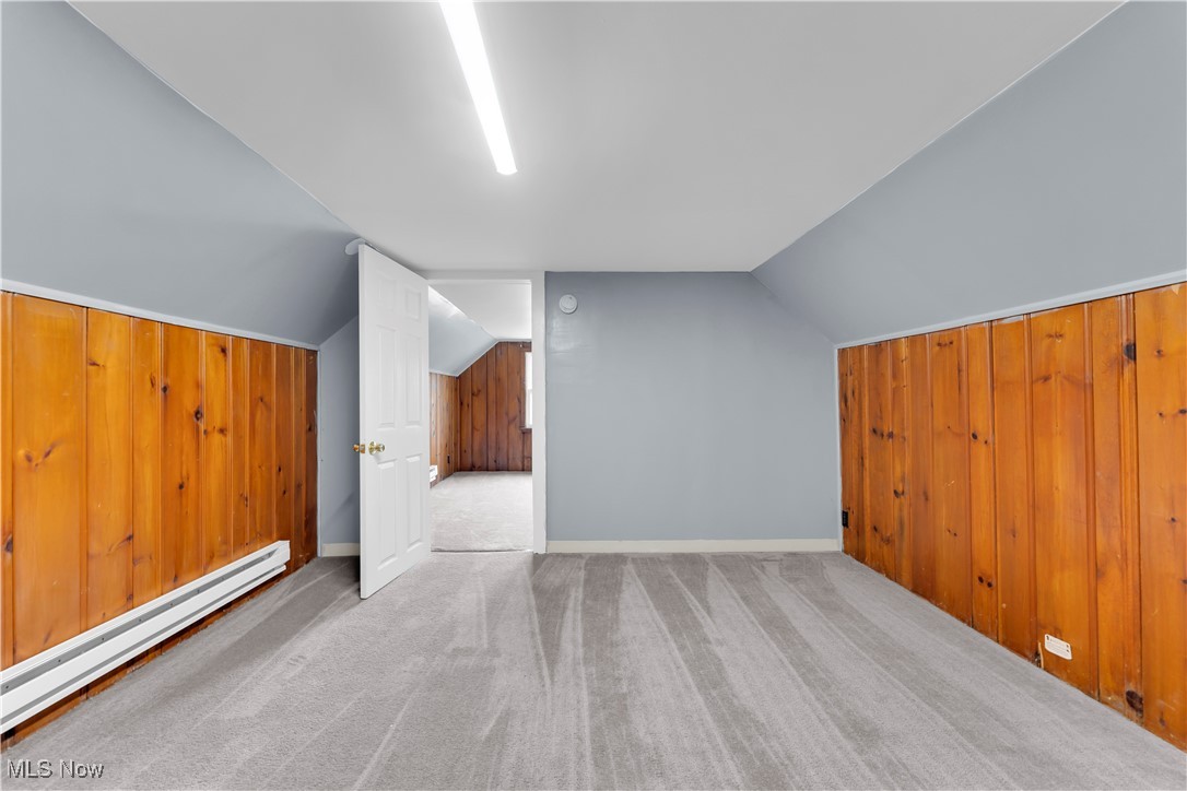 913 Helmsdale Road, Unit 3 Cleveland, OH 44112 - Photo 5 of 19 Additional living space with wood walls, carpet floors, baseboard heating, and vaulted ceiling