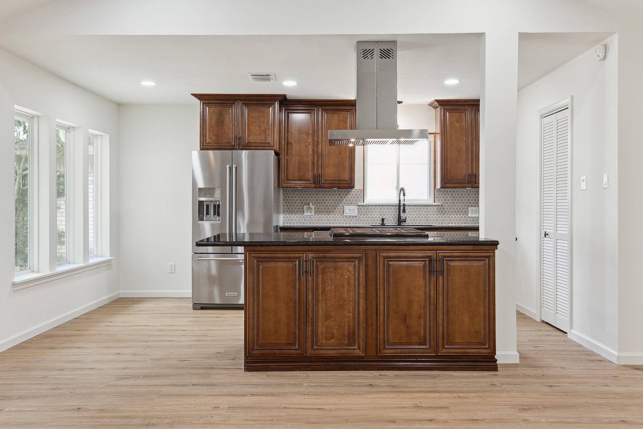 9719 Springmont Drive Houston, TX 77080 - Photo 13 of 32 Kitchen is anchored by an island with gas cooktop and drop-down ventilator! Usable cabinets facing the family room tucked under the countertop! Also in this picture, note the pantry closet tucked away to the side!