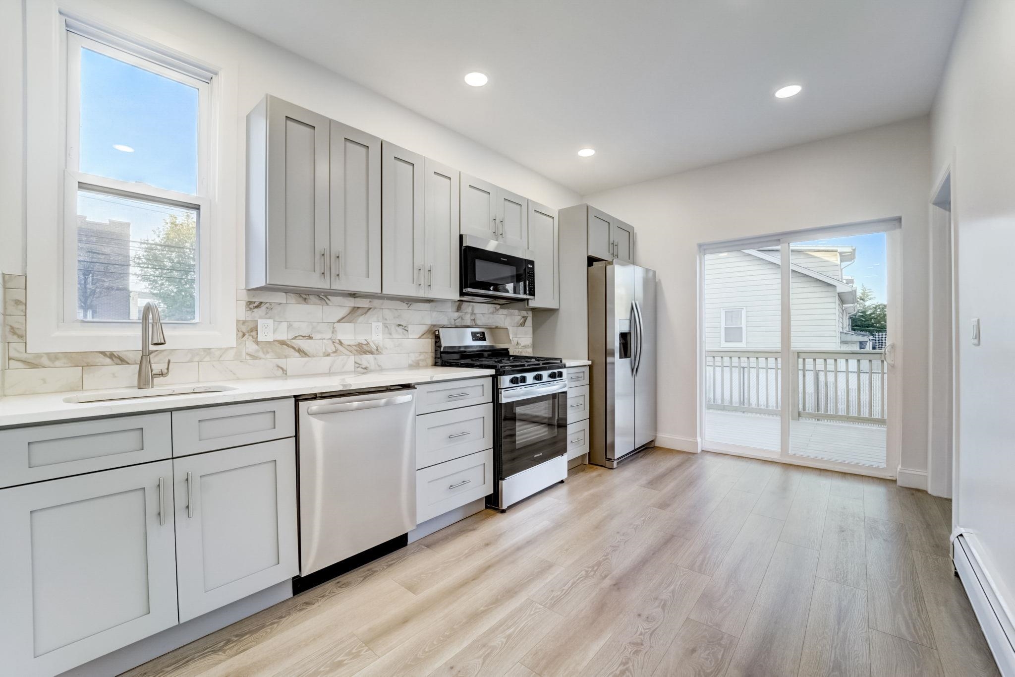 a kitchen with granite countertop white cabinets and wooden floor