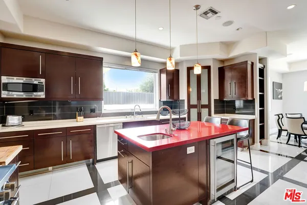 a kitchen with stainless steel appliances granite countertop table chairs and a refrigerator