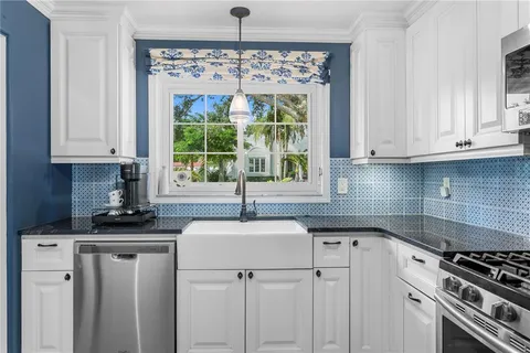a kitchen with stainless steel appliances granite countertop a sink stove and white cabinets