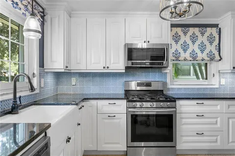 a kitchen with stainless steel appliances granite countertop a stove a sink and a microwave