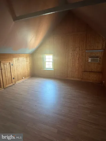 an empty room with wooden floor and windows with curtains