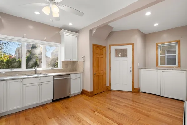 a large kitchen with a sink and dishwasher with wooden floor