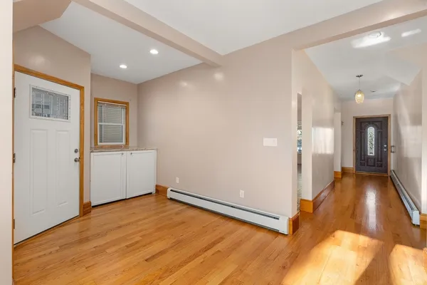 a view of a hallway with wooden floor and a bathroom