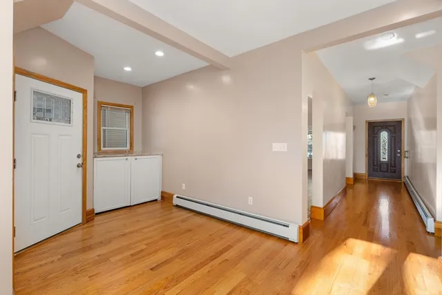 a view of a hallway with wooden floor and a bathroom