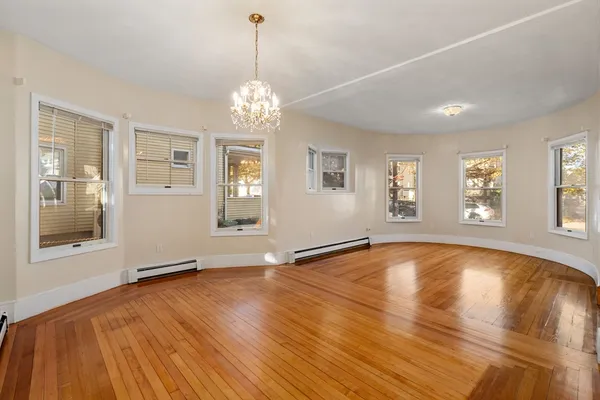a view of an empty room with a window and wooden floor