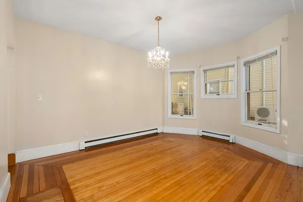 a view of an empty room with window and wooden floor