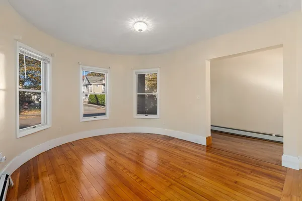 a view of an empty room with wooden floor and a window