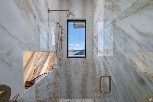 2867 East Granite Way St. George, UT 84790 - Photo 46 of 69 Walk-in shower with full-height stone-look tile walls, an integrated niche with backlighting, a fixed showerhead, and a handheld shower attachment