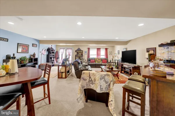 a living room with furniture a flat screen tv and a refrigerator
