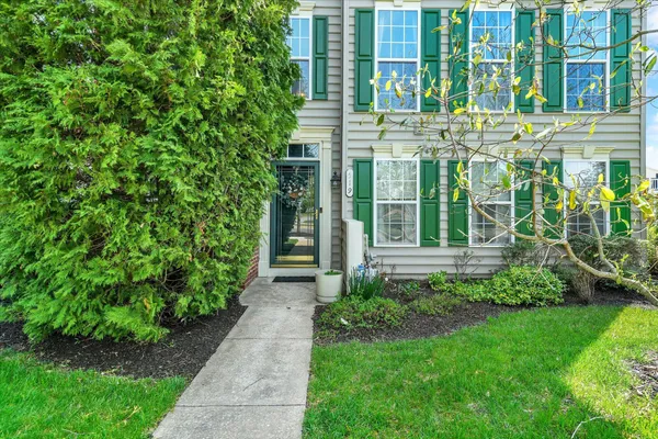 a view of yellow house with a yard and plants