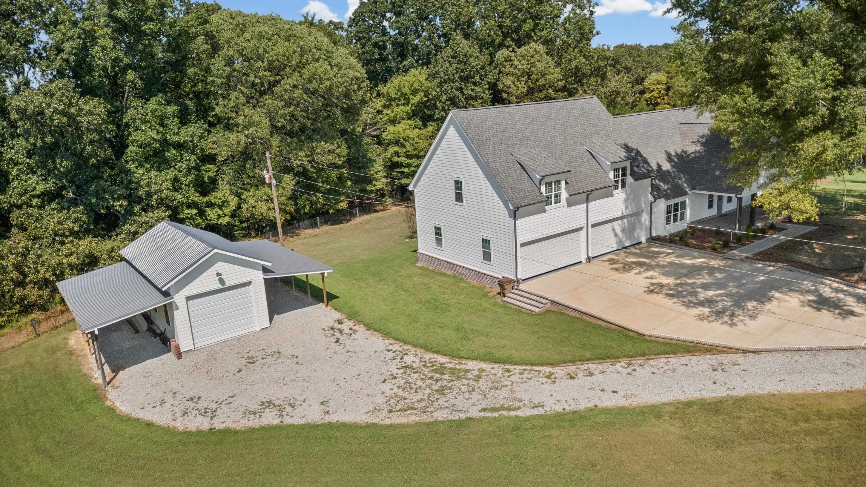 620 Diffee Road Moscow, TN 38057 - Photo 23 of 25 Expansive property featuring a white siding exterior, dark gray shingle roof, and a gravel driveway