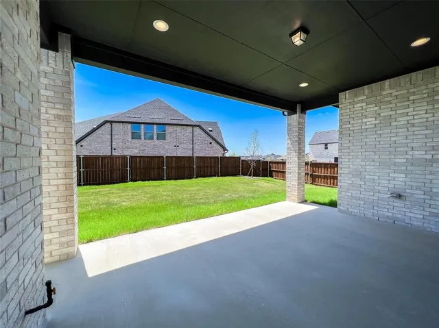 a backyard of a house with plants and large tree