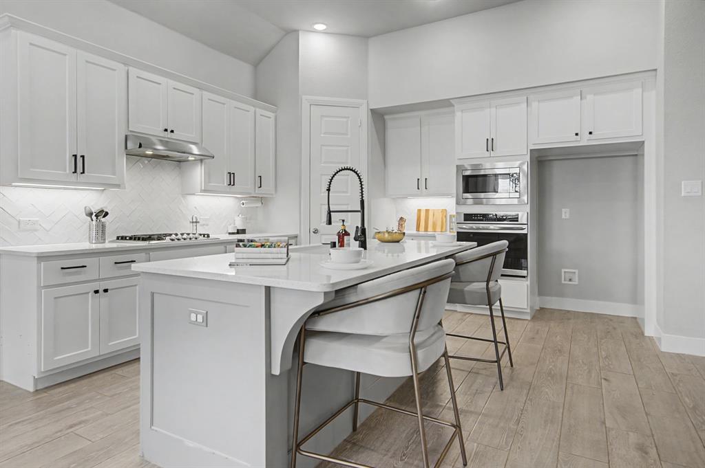 1101 Claiborne Drive Aubrey, TX 76227 - Photo 11 of 40 a kitchen with kitchen island a stove a sink and a refrigerator