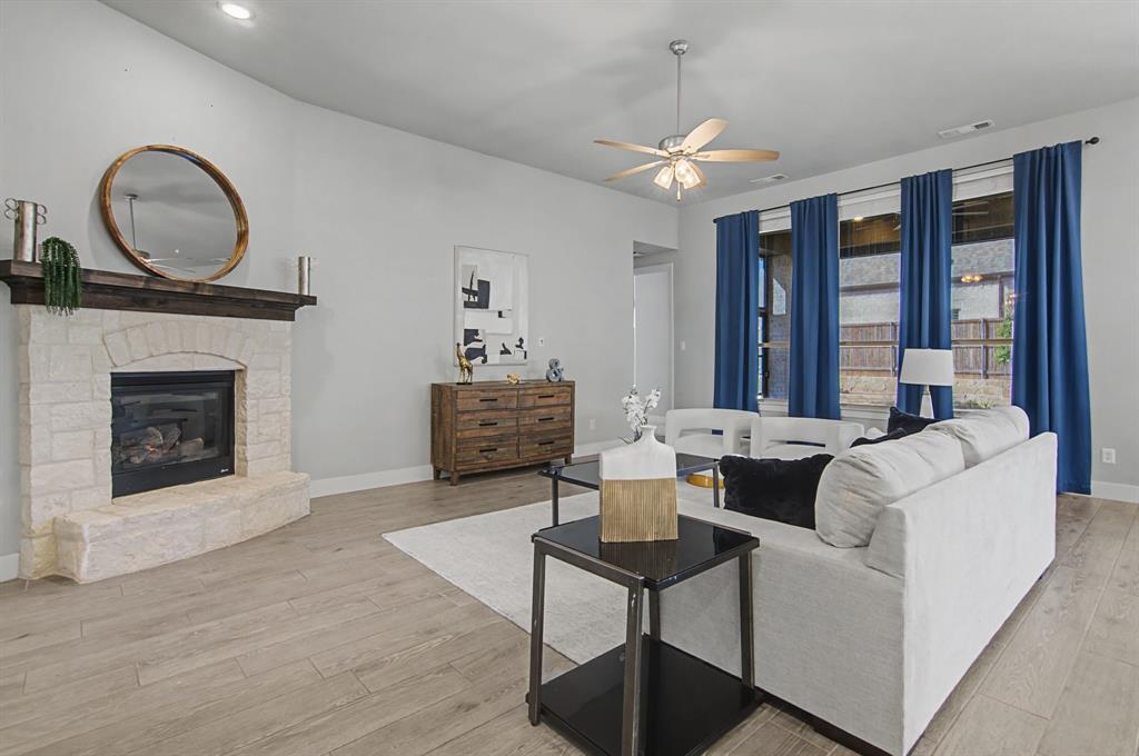 1101 Claiborne Drive Aubrey, TX 76227 - Photo 5 of 40 a living room with furniture a chandelier and a fireplace