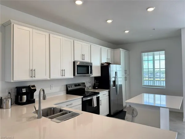 a kitchen with stainless steel appliances a stove a sink a refrigerator a window