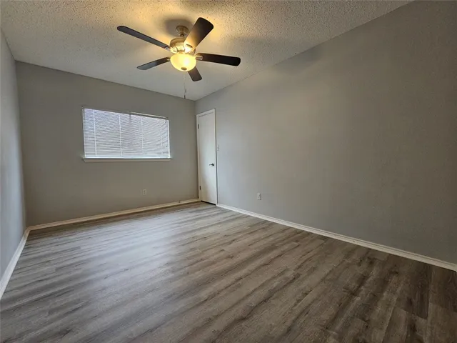 an empty room with wooden floor and ceiling fan