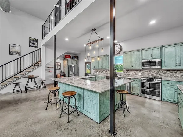 a kitchen with stainless steel appliances granite countertop table chairs stove and cabinets