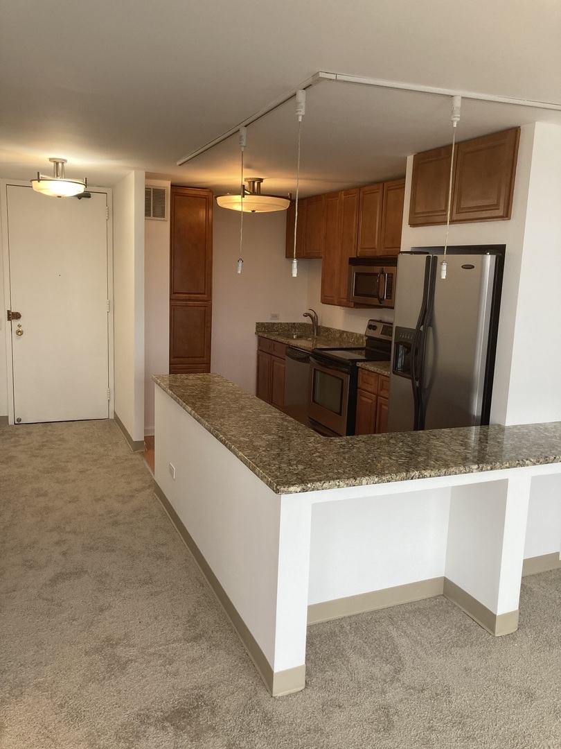 5445 North Sheridan Road, Unit 1409 Chicago, IL 60640 - Photo 3 of 7 a kitchen with stainless steel appliances granite countertop a sink and a refrigerator