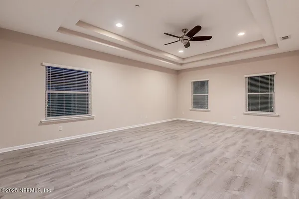 an empty room with wooden floor and a ceiling fan