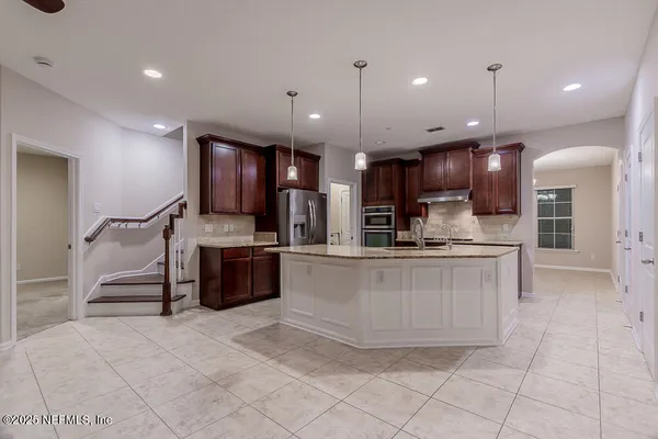 a large kitchen with a sink a counter top stainless steel appliances and cabinets