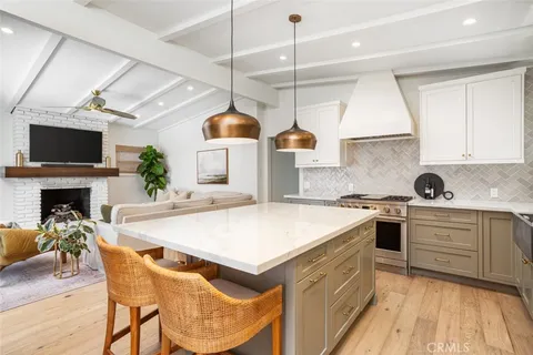 a kitchen with stainless steel appliances a stove a sink a refrigerator a fireplace a counter space and cabinets