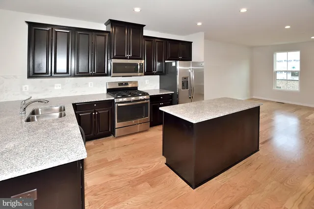 a kitchen with stainless steel appliances granite countertop a stove a sink and a refrigerator