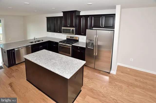 a kitchen with kitchen island a counter top space cabinets and stainless steel appliances