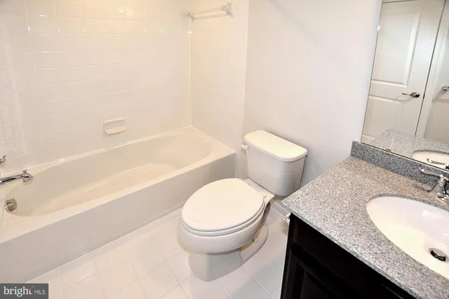 a bathroom with a granite countertop toilet sink and mirror