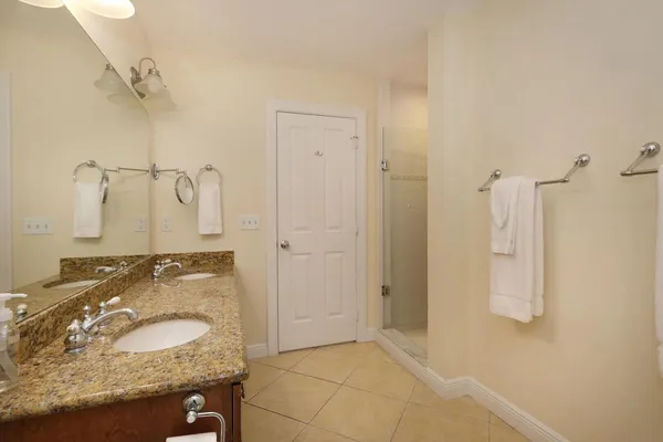 a bathroom with a granite countertop double vanity sink a toilet a mirror and shower
