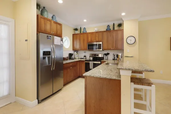 a kitchen with stainless steel appliances granite countertop a refrigerator a stove and a sink