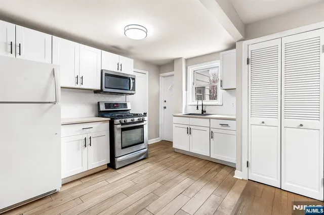 a kitchen with granite countertop white cabinets and stainless steel appliances