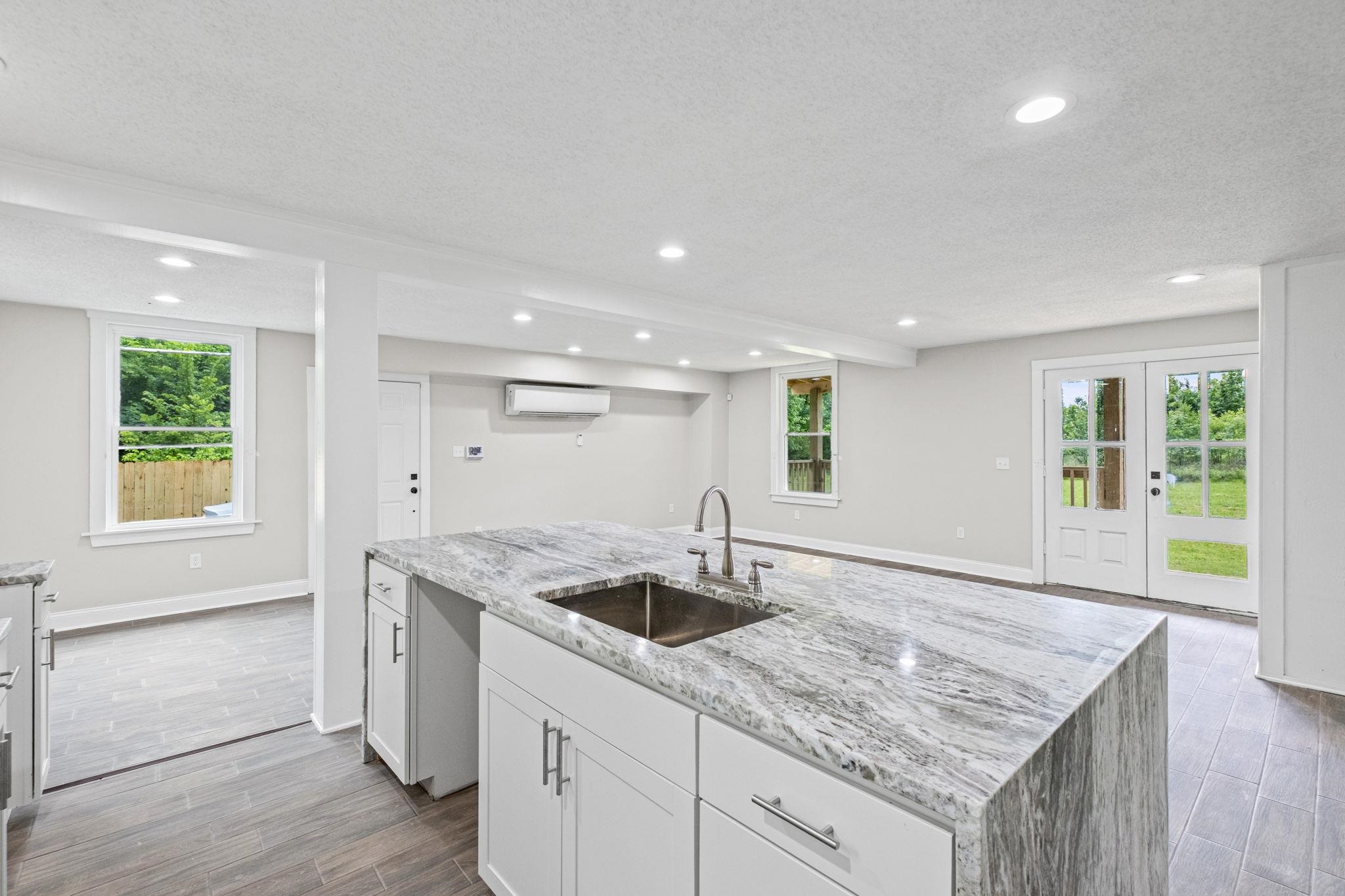 5843 Stewart Road Lakeland, TN 38002 - Photo 15 of 26 Kitchen island featuring a stainless steel sink with a gooseneck faucet, light-toned stone countertop, and white cabinetry
