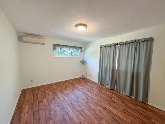 a view of an empty room with window and wooden floor