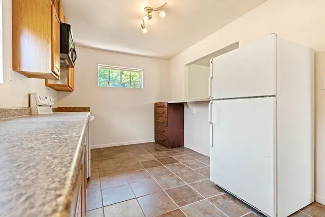 a view of an empty room with a window and a kitchen