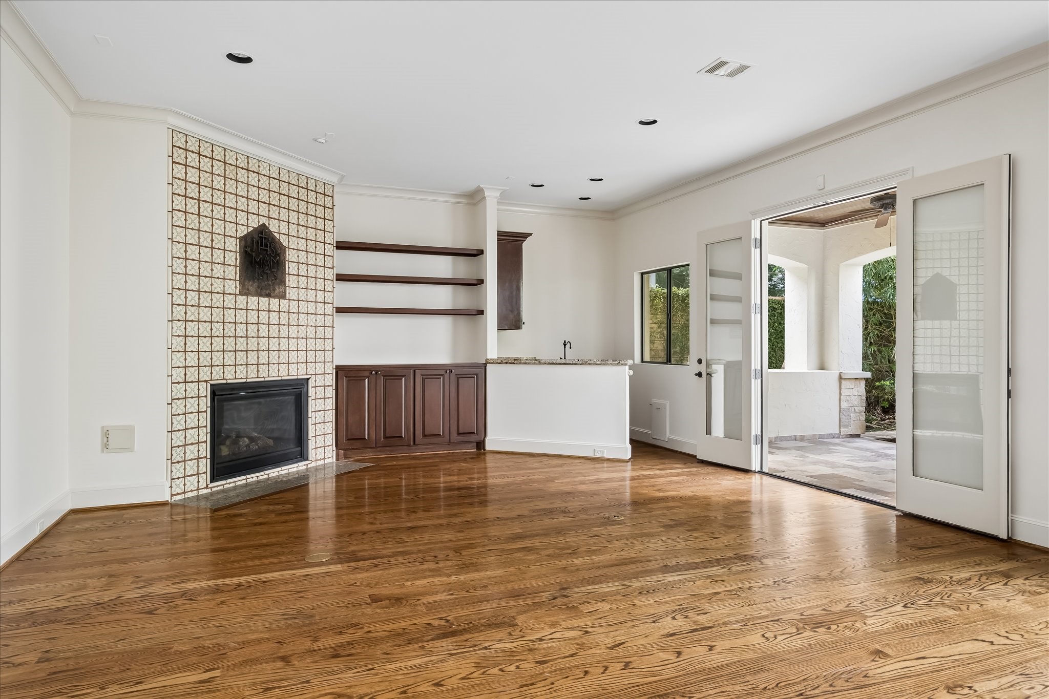 2246 Branard Street Houston, TX 77098 - Photo 18 of 40 Generous living area anchored by a tiled fireplace, floating shelving, and French doors opening to the covered outdoor patio.