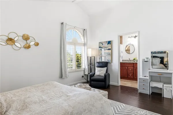 a bedroom with a bed and dresser with wooden floor