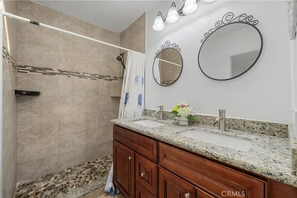 a bathroom with a granite countertop sink a mirror and shower