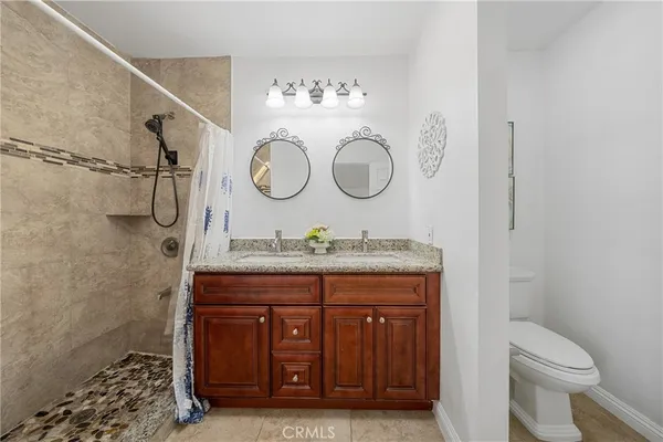 a bathroom with a granite countertop sink a toilet and a shower