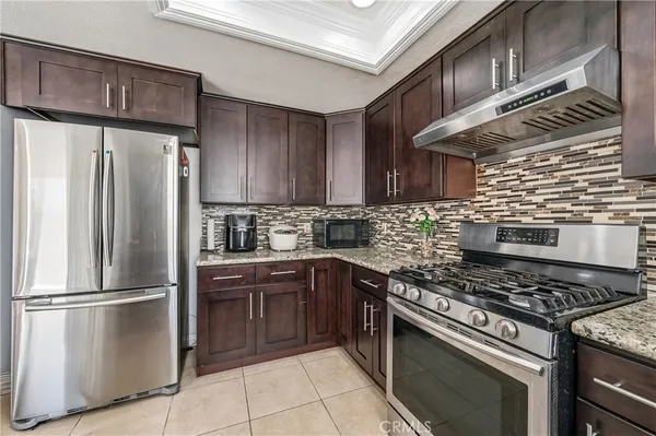 a kitchen with granite countertop a refrigerator and a stove top oven